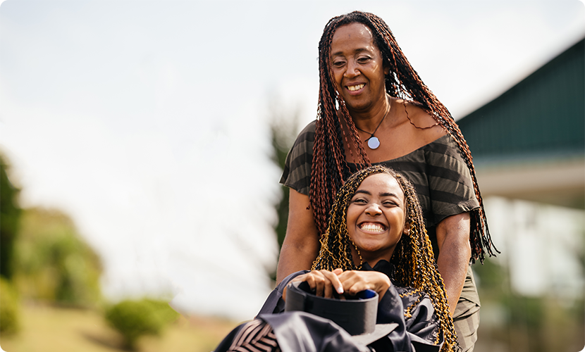 A smiling mother pushes her laughing daughter in a wheelchair